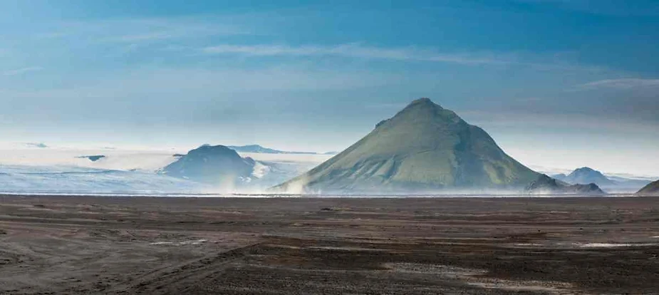 View of the majestic Uxatindar Mountains rising in Iceland's remote Highlands, with a vast volcanic plain stretching in the foreground.