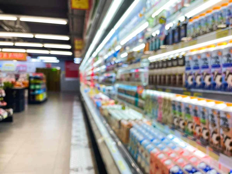 Wide-angle view of a brightly lit Icelandic supermarket aisle showcasing refrigerated shelves stocked with dairy and beverage products.