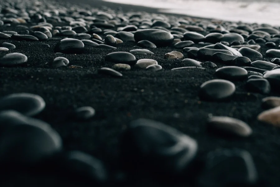 Close-up of smooth black volcanic pebbles on the shore of Reynisfjara Black Sand Beach in Iceland, showcasing the unique geological formation.