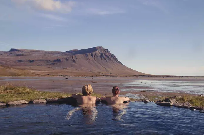 two adults bathing naked in an Icelandic hot spring