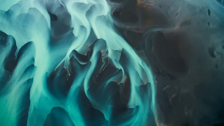 A breathtaking aerial view of Iceland's glacial rivers with stunning blue and green hues blending together.