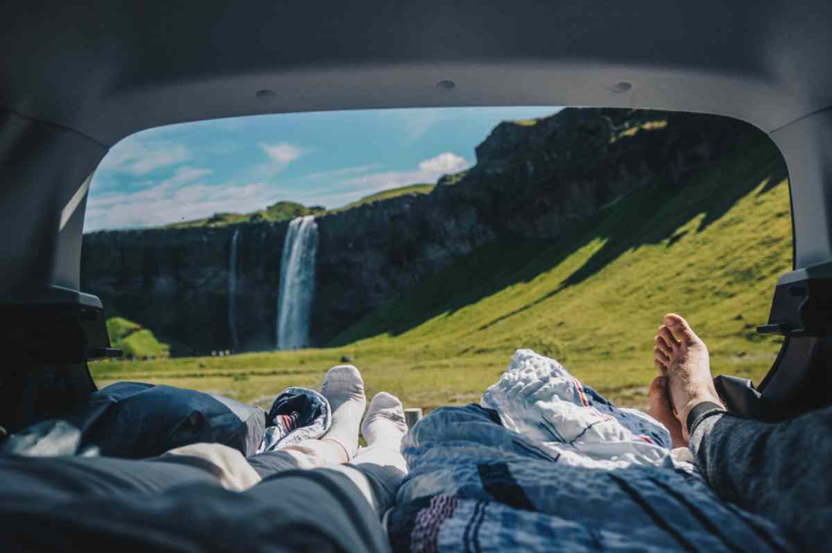 a couple laying down on their camper with views to a waterfall