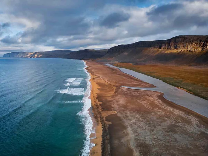 Aerial view of Rauðisandur beach in the Westfjords of Iceland, with golden sands and blue waters against rugged cliffs