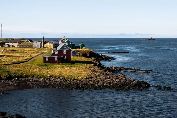 Scenic view of Flatey Island with traditional Icelandic houses by the coast and the calm sea in the background.