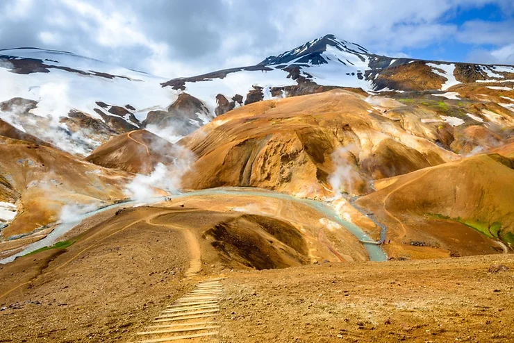 Scenic view of steaming geothermal areas and snowy peaks along the highland roads in Iceland.