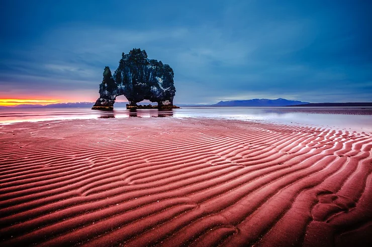 Hvítserkur rock formation standing majestically on the red rippled sands of the beach at sunset in Iceland.