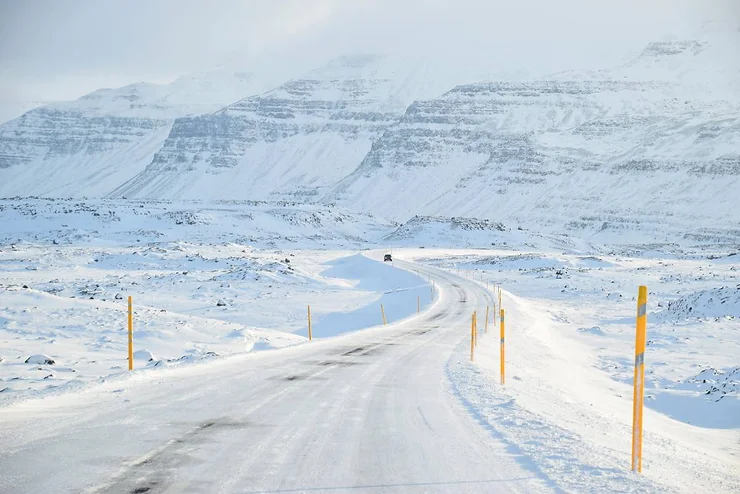 A snowy road flanked by mountains, illustrating the typical January weather in Iceland.