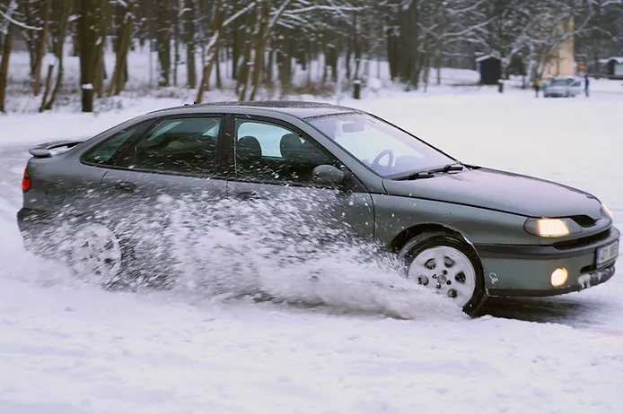 Car sliding in the snow while breaking with headlights on