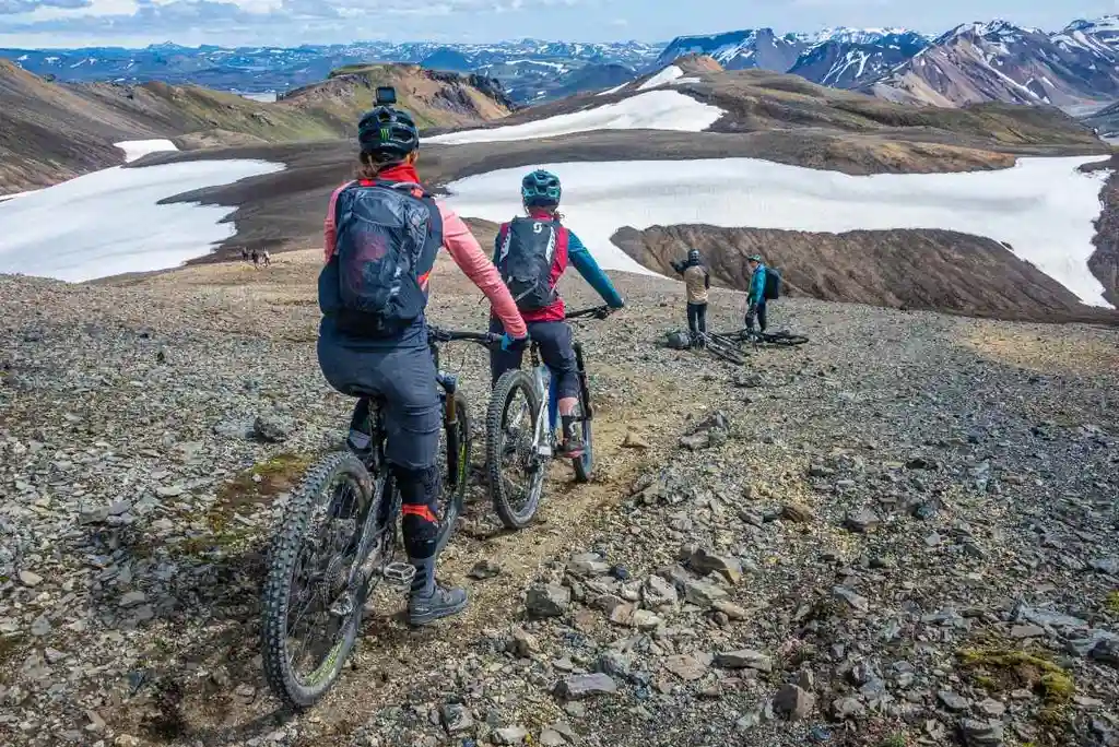 A group of cyclists, equipped with mountain bikes and protective gear, embark on a guided tour across the rugged terrain of Iceland.