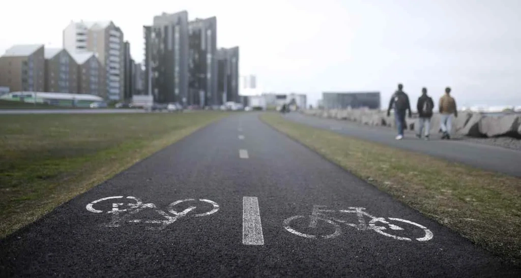 A paved bike path in Iceland marked with white bicycle symbols