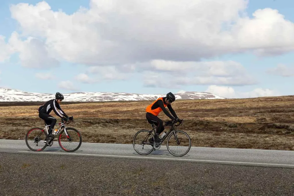 Two cyclists ride along a road in Iceland's Golden Circle region.