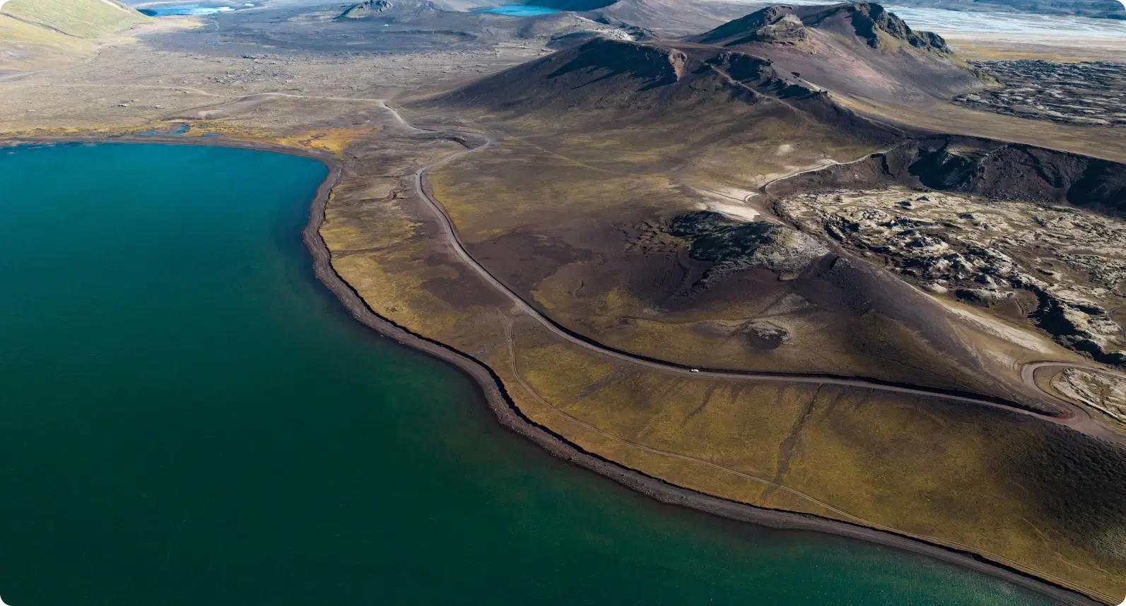 Aerial view of Iceland’s scenic coastline and winding roads, showcasing the vast landscapes accessible with a rental car along the Ring Road.