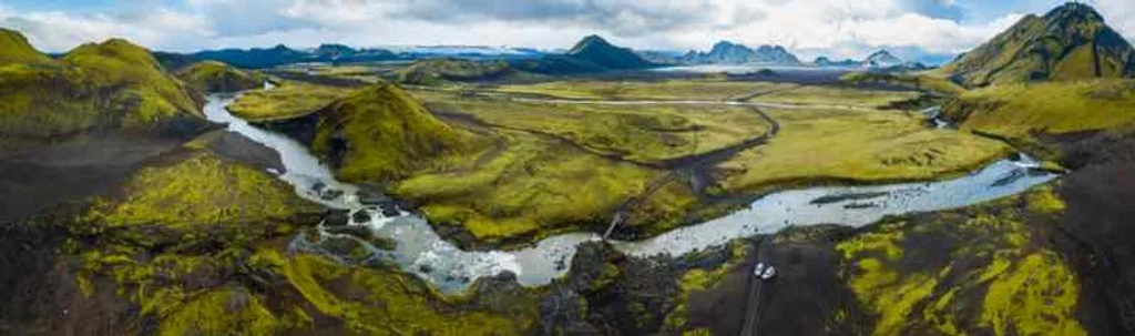 Luftaufnahme der grünen und zerklüfteten Landschaft von Eldgjá in Island, mit gewundenen Flüssen und Bergen im Hintergrund, die die dramatische und unberührte Schönheit der Gegend zeigt.