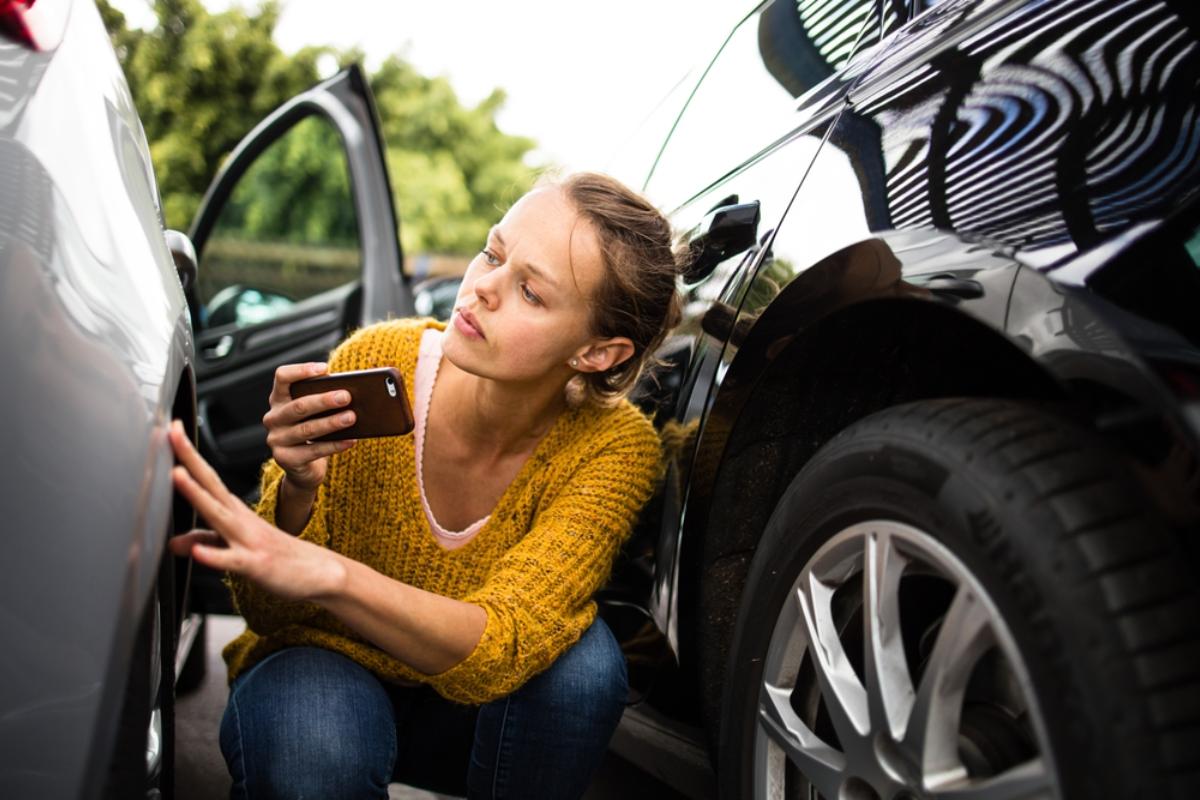 Junge Frau, die den Schaden an ihrem Mietwagen überprüft