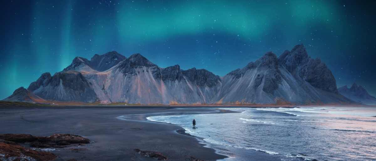 Der Berg Vestrahorn und der schwarze Sandstrand Reynisfjara an seinem Fuß in Island unter Polarlicht.