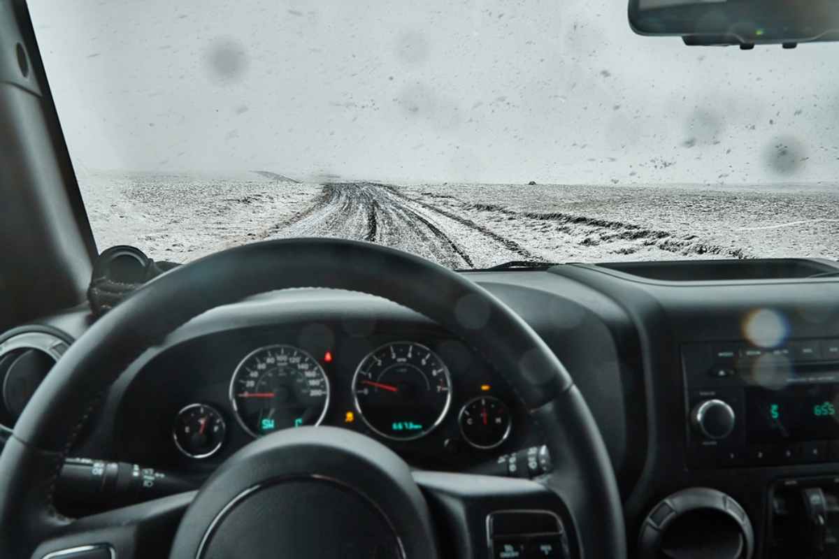 Blick auf eine verschneite Straße aus dem Fahrersitz