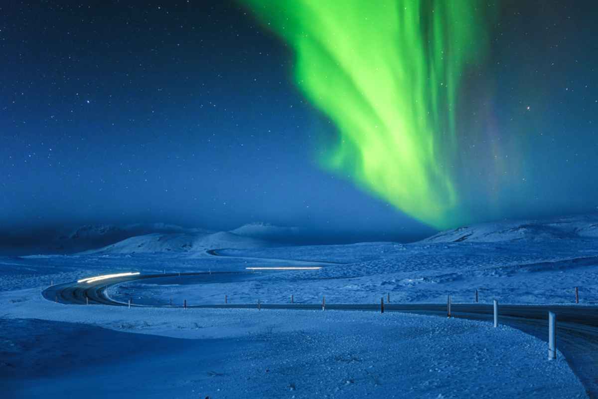 Grüne Nordlichter, die über einer verschneiten Landschaft tanzen