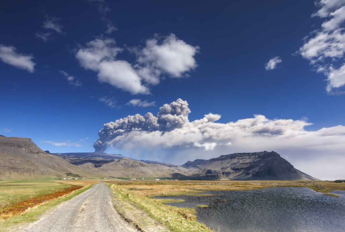 Straße, die zum Vulkan Eyjafjallajökull führt, mit einer Aschesäule und einem Panache