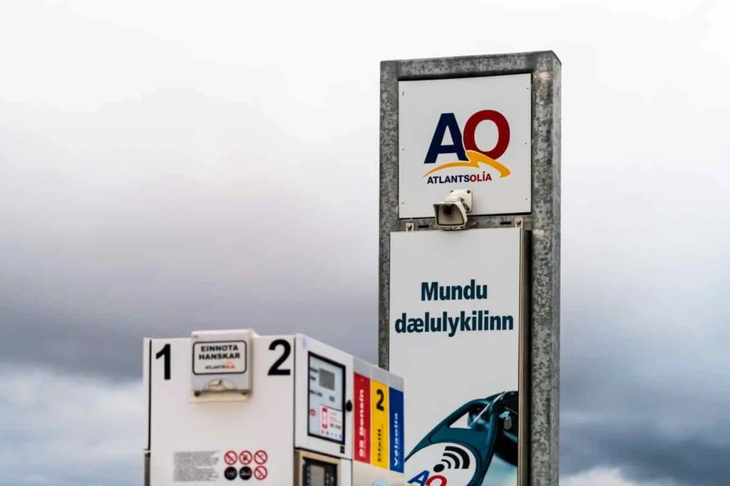 Schild und Zapfsäulen der Atlantsolía-Tankstelle in Island bei bedecktem Himmel, mit dem Markenlogo und isländischem Text