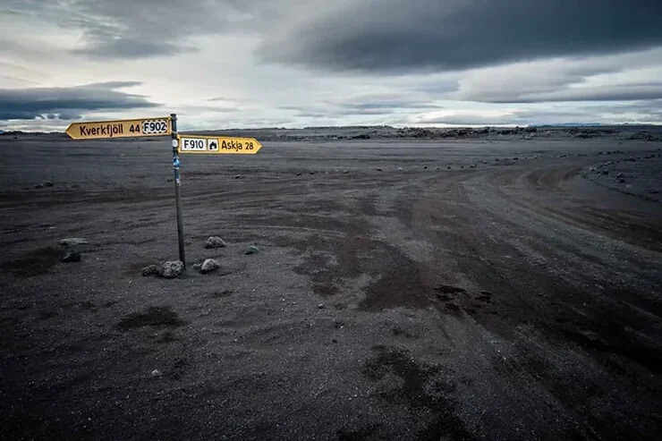 Un panneau routier indiquant Kverkfjöll et Askja, placé dans un paysage volcanique isolé sous un ciel nuageux.