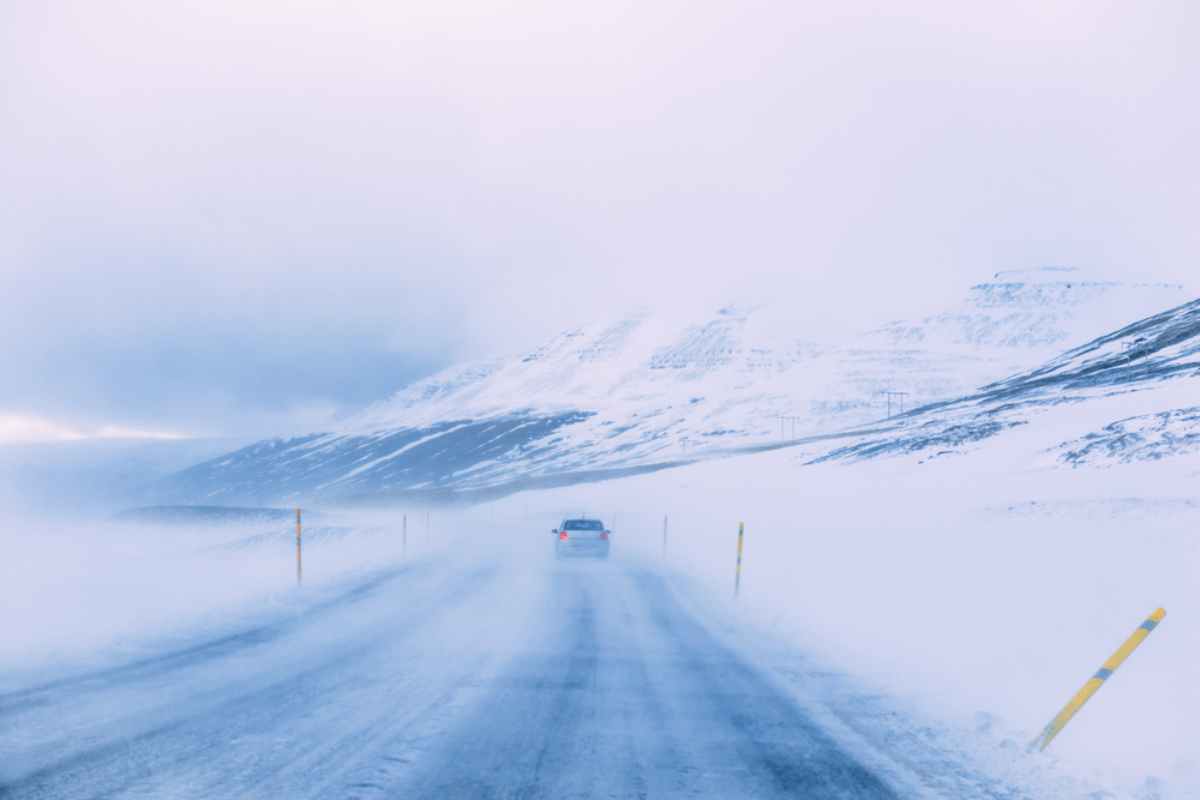 Voiture compacte grise au milieu d'une tempête de neige sur la Ring Road islandaise