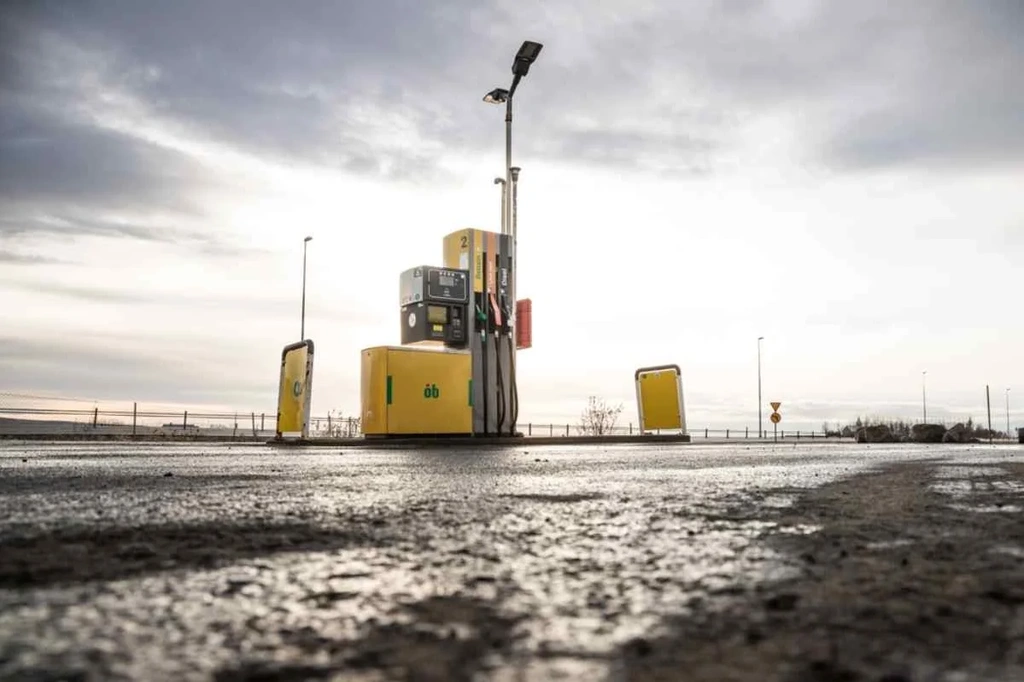 Pompa gialla di un distributore di benzina in Islanda sotto un cielo nuvoloso, che enfatizza l'ambiente minimalista e aperto